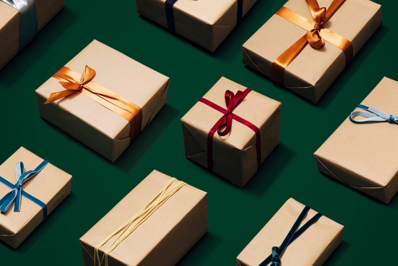 From above photo of wrapped xmas gifts in kraft paper on a green table.